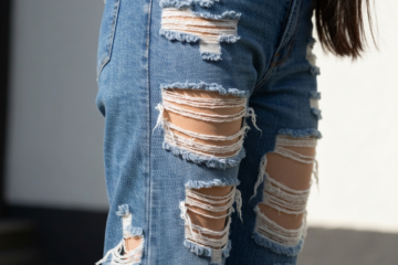 Zdjęcie z bliska podartych dżinsów na osobie stojącej na zewnątrz w naturalnym świetle dziennym